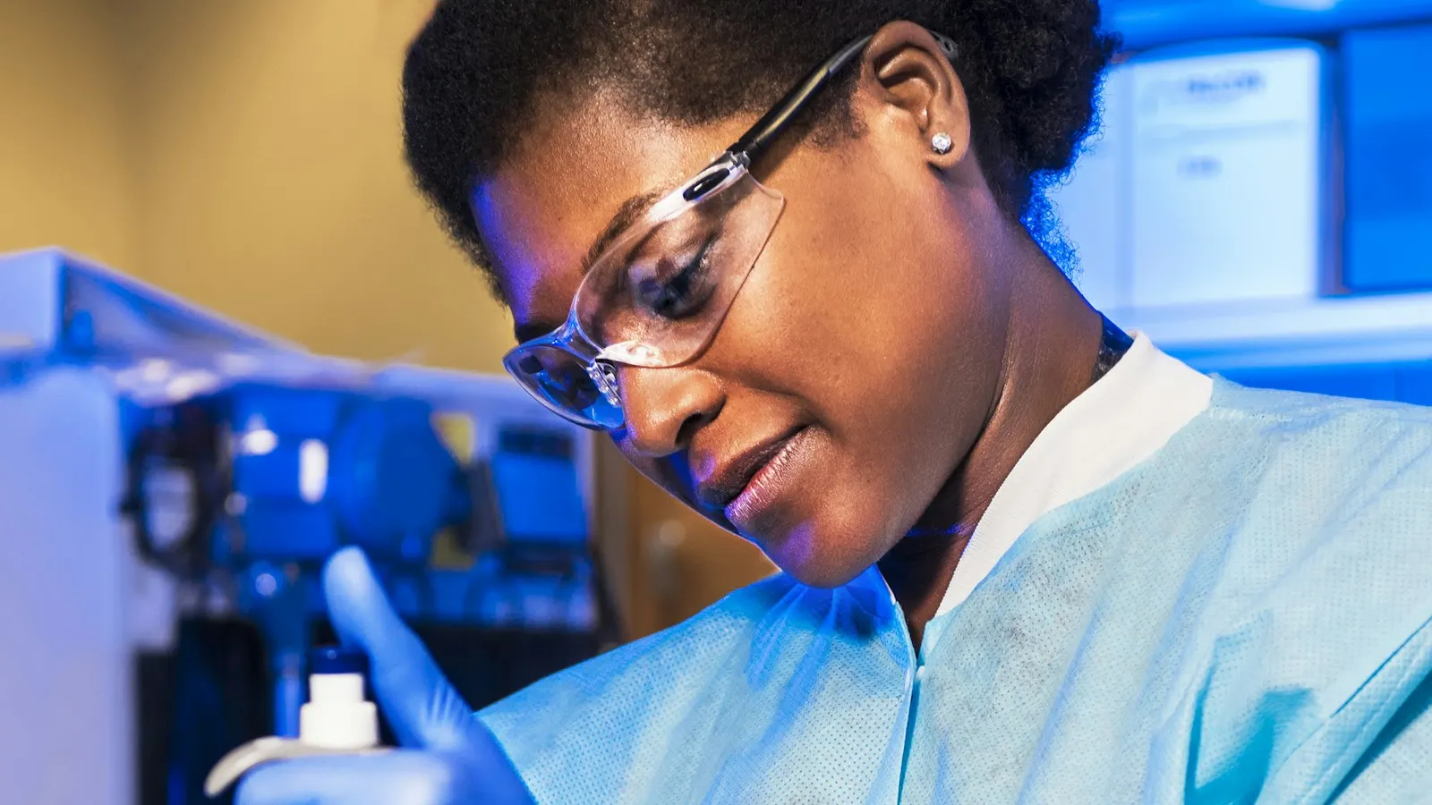 A laboratory scientist pipetting samples into rows of amber vials